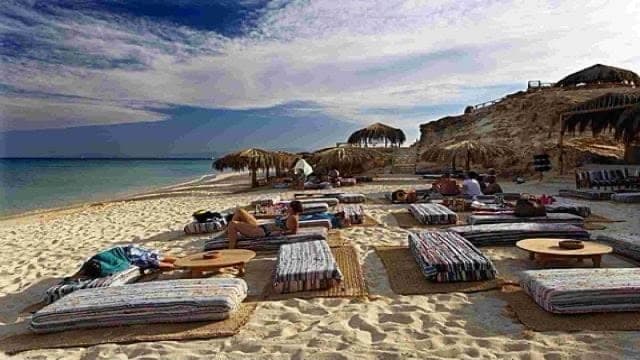 Beach lounge seating under straw parasols on Mahmya Island
